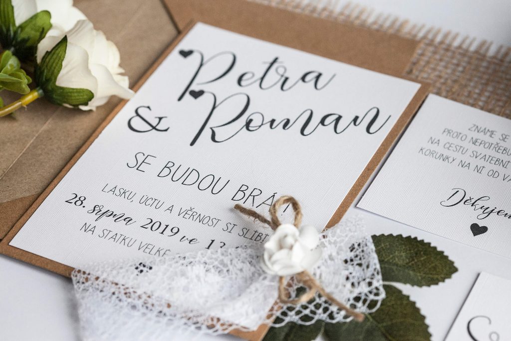 Přírodní svatební oznámení s krajkou a papírovou kytičkou na kraftovém papíře